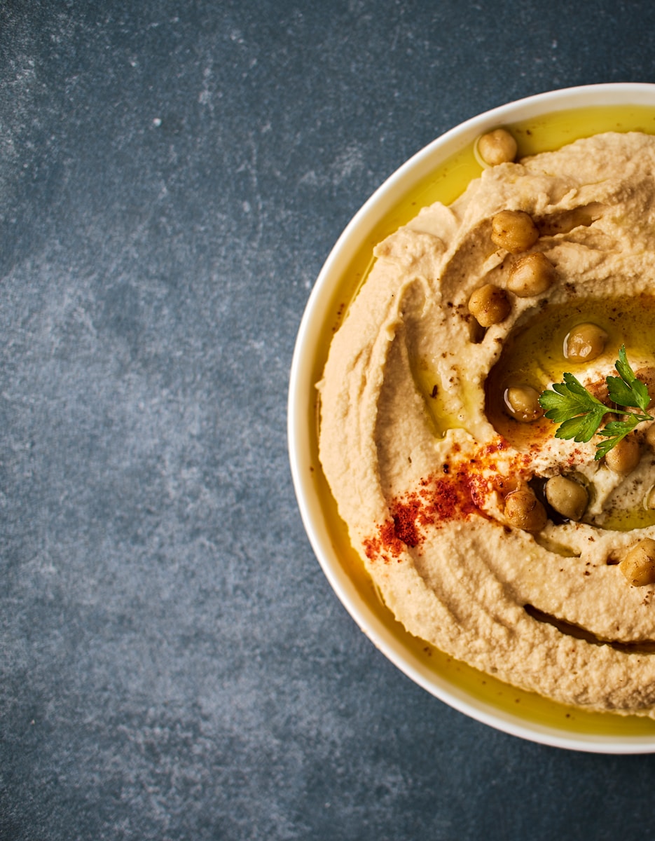 Hummus Basis Rezept a white bowl filled with hummus and olives